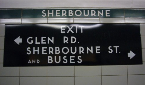 White letters on a black sign read EXIT &larr; GLEN RD. SHERBOURNE ST. AND BUSES &rarr;