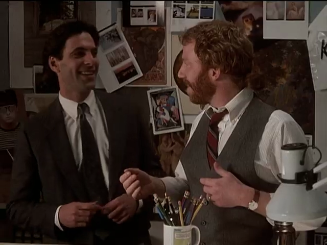 Michael (suit) and Elliot (conventional shirt and veston) smiling at each other